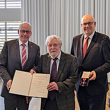 Bremerhavens Stadtverordnetenvorsteher Torsten von Haaren (links) und der Präsident des Bremer Senats, Bürgermeister Andreas Bovenschulte (rechts), überreichten im Deutschen Auswandererhaus das Bundesverdienstkreuz am Bande an Friedel Ditsche. 